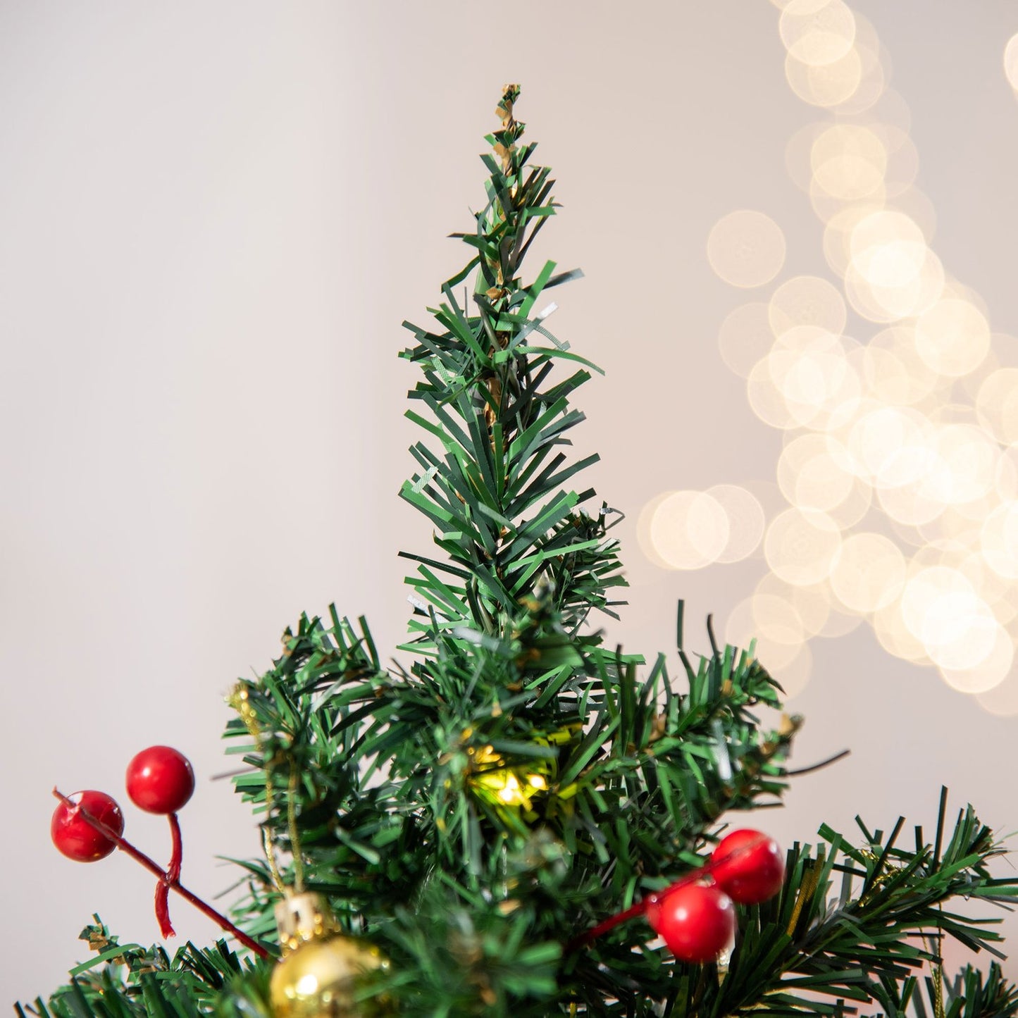 Small green Christmas tree with LED lights and berries